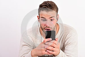 Young man texting message on phone while listening to music