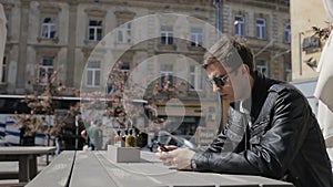 Young man texting on smartphone and using smart watches in cafe.Young Caucasian Man Buying Goods From the Internet on His phone