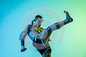 Young man thai boxer training over blue background in neon light.