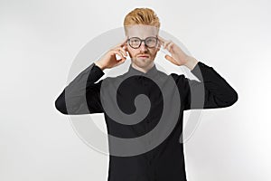 Young man in thinking process. Close up redheaded guy with red beard in black shirt, glasses focus on creating startup idea