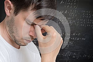 Young man in thinking. Solving a difficult math problem. Math formulas in background