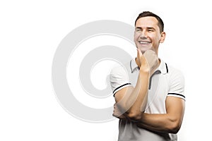 Young man thinks and smiles and looks up in copy space