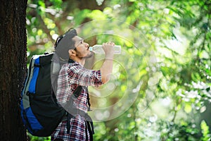 Young man thirsty and drink water during the trek behind a large