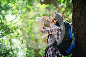 Young man thirsty and drink water during the trek behind a large