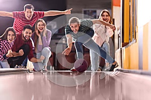 Young man throwing ball and spending time with friends in bowling