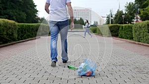 A young man throws out a package of garbage in the center of the city, litterbug