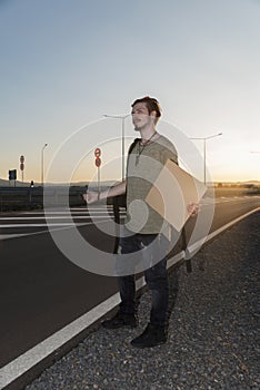 Young man thumbing on a highway