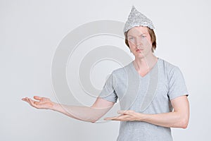 Young man with tinfoil hat as conspiracy theory concept showing something