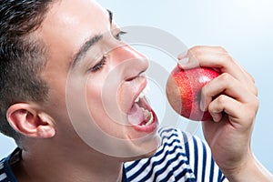 Young man about to bite apple.