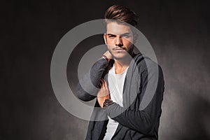 Young man touching his shoulder while posing in studio