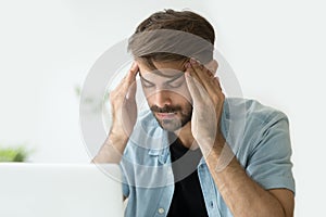 Young man touching temples trying to focus or feeling headache photo