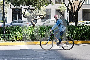 Young man touring a city street on a bicycle looking at camera