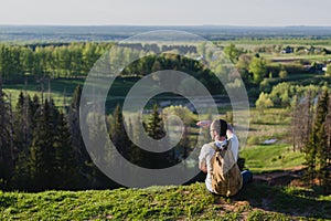 Young man tourist with backpack standing on the edge of beautiful canyon and victoriously raised hands. Male hiker