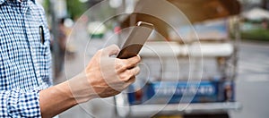 Young man tourist or casual businessman ordering taxi via cab application on smartphone in city street, Male traveler using mobile