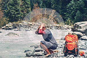 Young man tourist refresh with water in mountain river