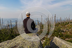 Young man tourist sittiing on top of mountain, Sumava National Park and Bavarian Forest, Czech republic and Germany