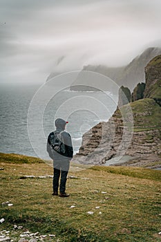 Young man tourist standing on Footpath to cliff Traelanipan and lake Sorvagsvatn located on the island of Vagar