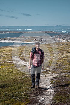 Young man tourist standing in front of iceberg. View towards Icefjord in Ilulissat. Icebergs from Kangia glacier in