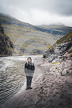 Young man tourist standing in the saksun valley on a hiking path in the faroe islands on the main island of Streymoy.