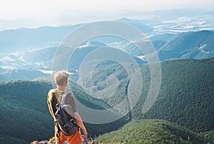 Young man tourist stands on the top of hill and enjoys with infinity hills panorama