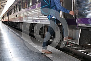 young man, tourist or traveler stepping up to the train on railway at train station. Travel, journey, trip concept
