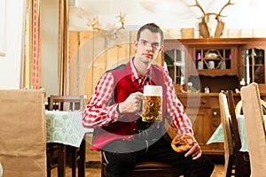 Young man in traditional Bavarian Tracht in restaurant or pub