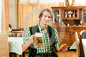 Young man in traditional Bavarian Tracht in restaurant or pub