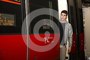 Young man on train, standing in open door treshold