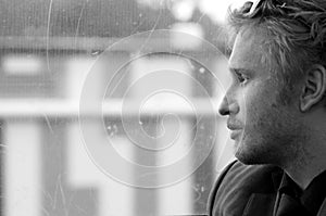 Young man on train trip looking out window daydreaming