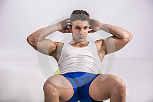 Young man training abs on fitness ball