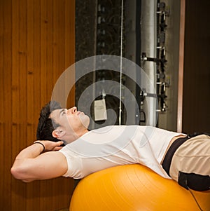 Young man training abs on fitness ball