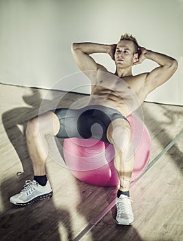 Young man training abs on fitness ball