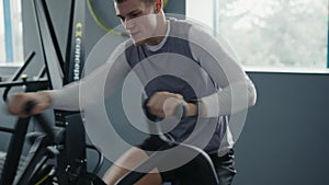 Young Man Training Intensely on a Stationary Bike at Gym