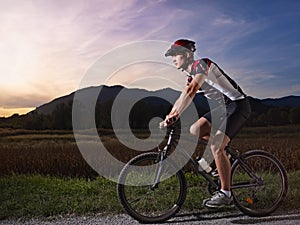 Young man training on mountain bike at sunset