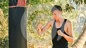 young man training with a punching bag in the jungle