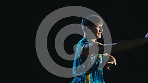 Young man training wushu against black background