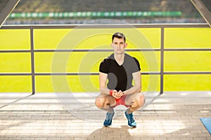 Young man training yoga outdoors. Sporty guy makes stretching exercise on a blue yoga mat, on the sports ground