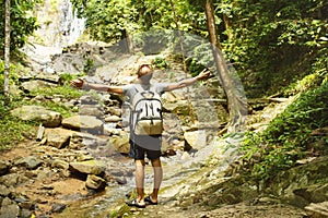 Young man with a travel backpack near a waterfall in Thailand