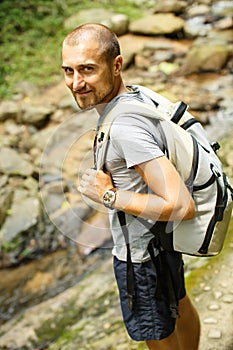 Young man with a travel backpack near a waterfall in Thailand