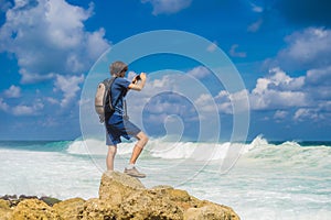 Young man traveler on amazing Melasti Beach with turquoise water, Bali Island Indonesia