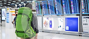 Young man traveler with backpack checking flight time, Asian passenger with hat looking to information board in international