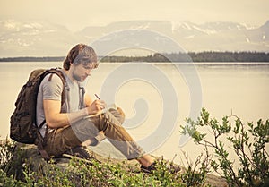 Joven hombre viajero mochila lectura un libro 