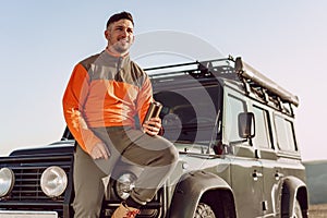 Young man traveler drinking from his thermocup while halt on a hike