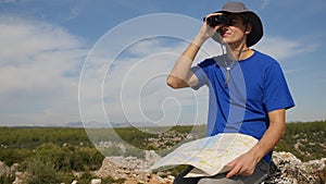 Young man traveler with map looking far away through binoculars