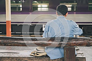 A young man traveler with map sitting in station choose where to travel. Concept of backpackers travel adventure by train