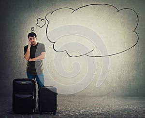 Young man traveler standing behind his luggage and waiting