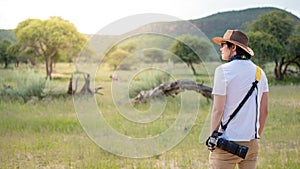 Young man traveler standing in safari looking at wildlife animal