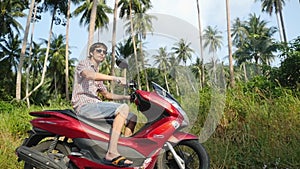 Young man traveler in sunglasses driving motorbike on tropical sunny road. slow motion. 1920x1080