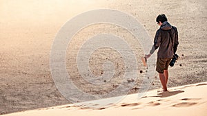 Young man traveler walking down the sand dune with bear foot