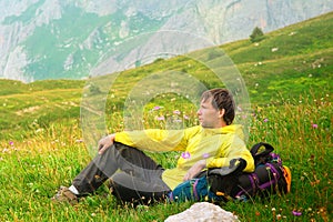 Young Man Traveller with backpack sitting on grass